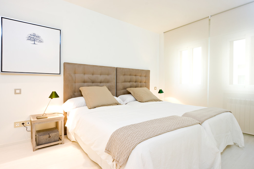 This is an example of a mid-sized transitional guest bedroom in Madrid with white walls and no fireplace.