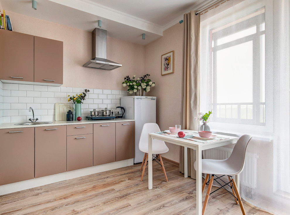 Photo of a small contemporary single-wall eat-in kitchen in Saint Petersburg with a single-bowl sink, flat-panel cabinets, brown cabinets, white splashback, ceramic splashback, laminate floors, no island and brown floor.