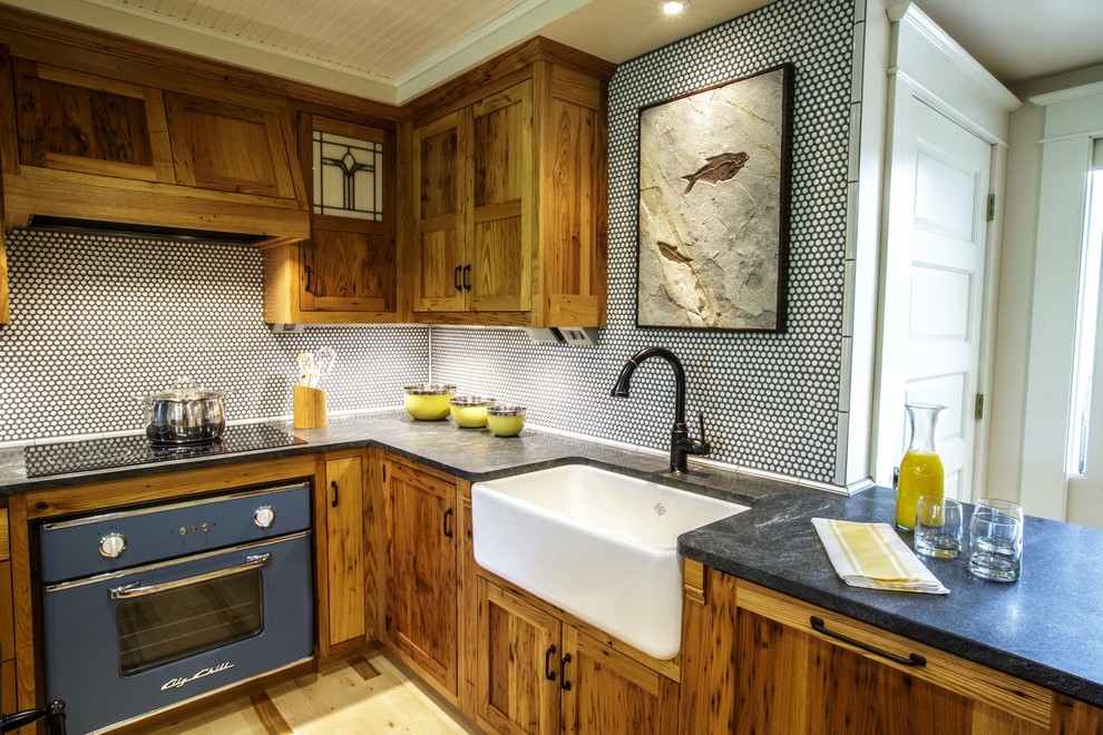 Country kitchen in Other with a farmhouse sink, shaker cabinets, medium wood cabinets, granite benchtops, white splashback, mosaic tile splashback, coloured appliances and light hardwood floors.