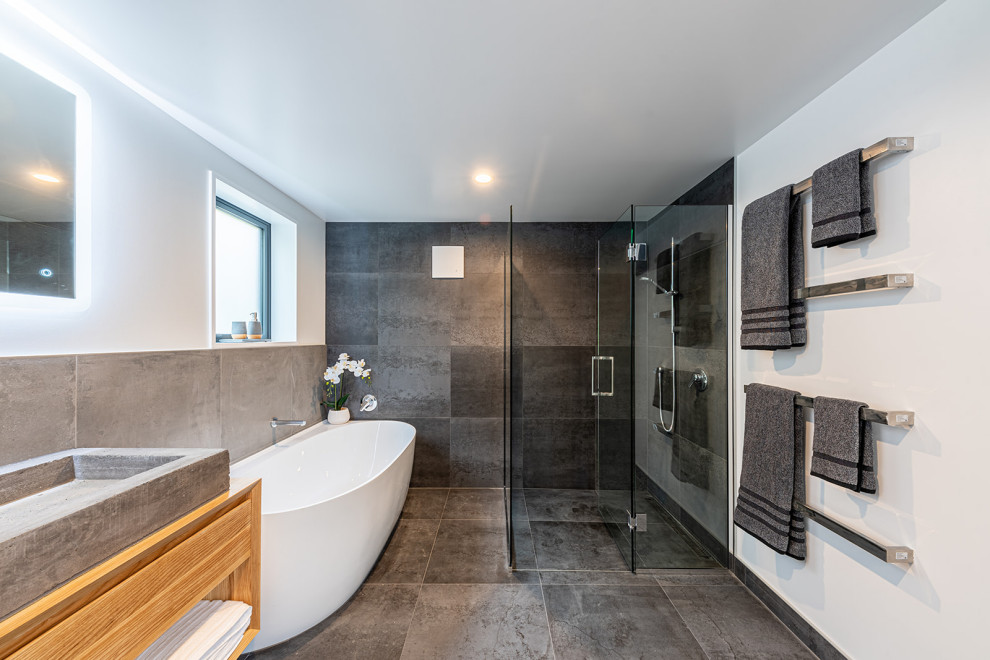 Inspiration for a medium sized urban bathroom in Christchurch with a freestanding bath, grey tiles, a hinged door, a single sink and a built in vanity unit.