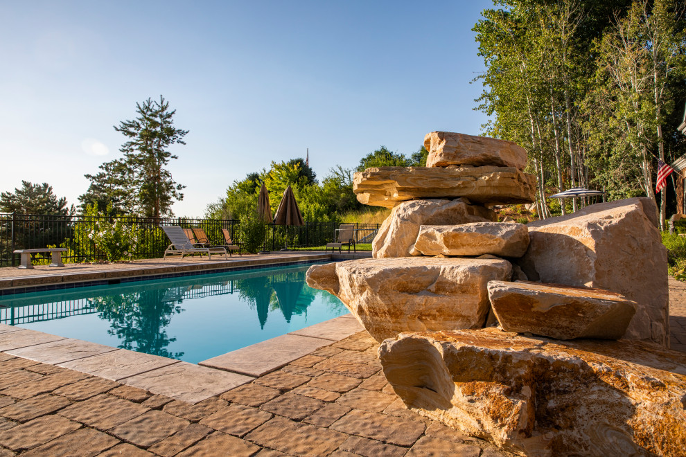 Mid-sized traditional backyard rectangular lap pool in Salt Lake City with with a pool and natural stone pavers.