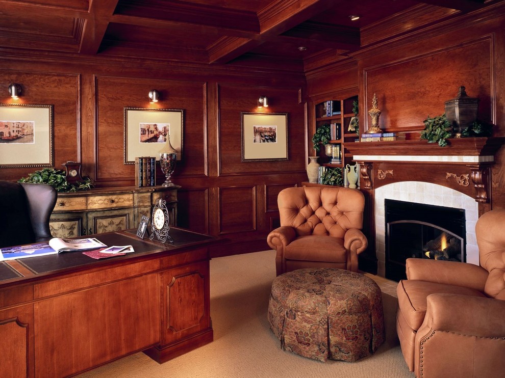 Photo of a large traditional home office in Denver with a library, red walls, carpet, a standard fireplace, a wood fireplace surround, a freestanding desk and beige floor.