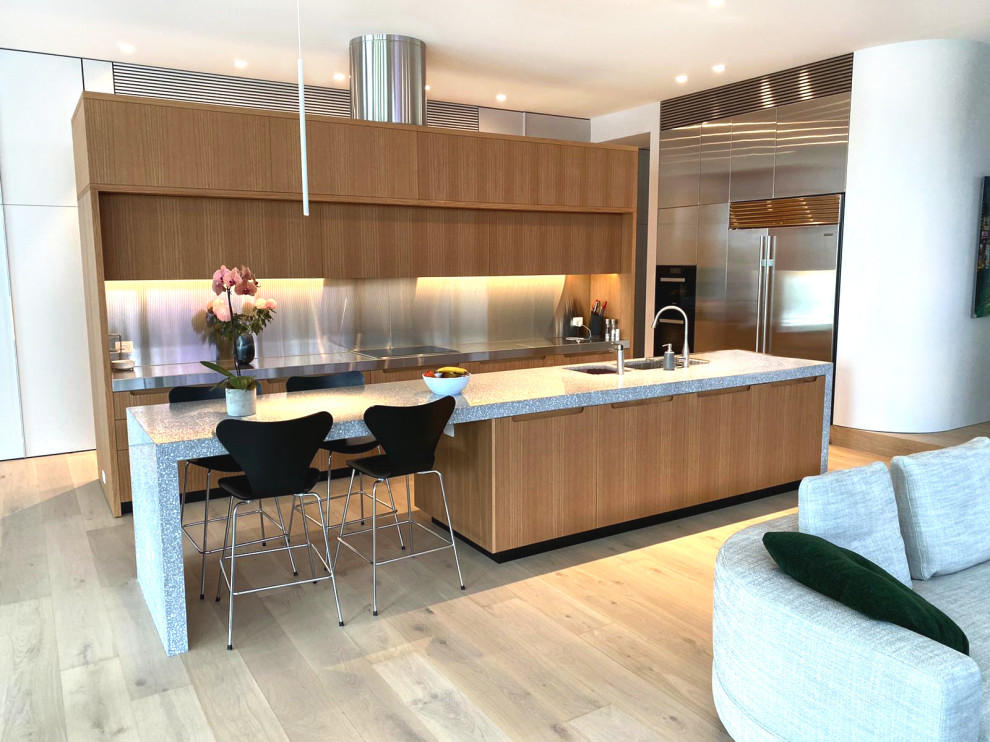 This is an example of an expansive modern galley kitchen in Sydney with an undermount sink, medium wood cabinets, stainless steel benchtops, grey splashback, stainless steel appliances, with island and grey benchtop.