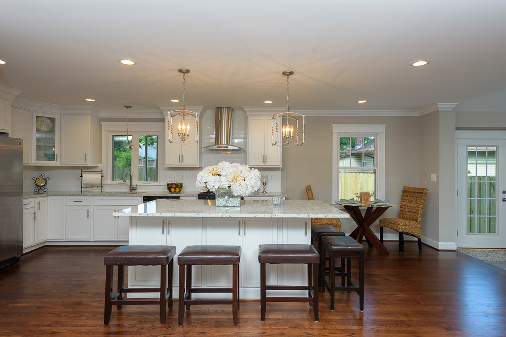 Eat-in kitchen - large transitional l-shaped medium tone wood floor and brown floor eat-in kitchen idea in Baltimore with an undermount sink, shaker cabinets, white cabinets, granite countertops, white backsplash, ceramic backsplash, stainless steel appliances and an island