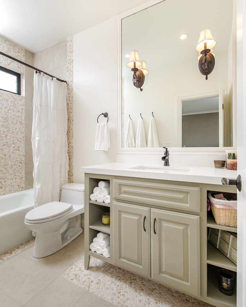 Small traditional bathroom in Los Angeles with an undermount sink, raised-panel cabinets, beige cabinets, an alcove tub, a shower/bathtub combo, a one-piece toilet, beige tile, pebble tile, white walls, pebble tile floors and engineered quartz benchtops.