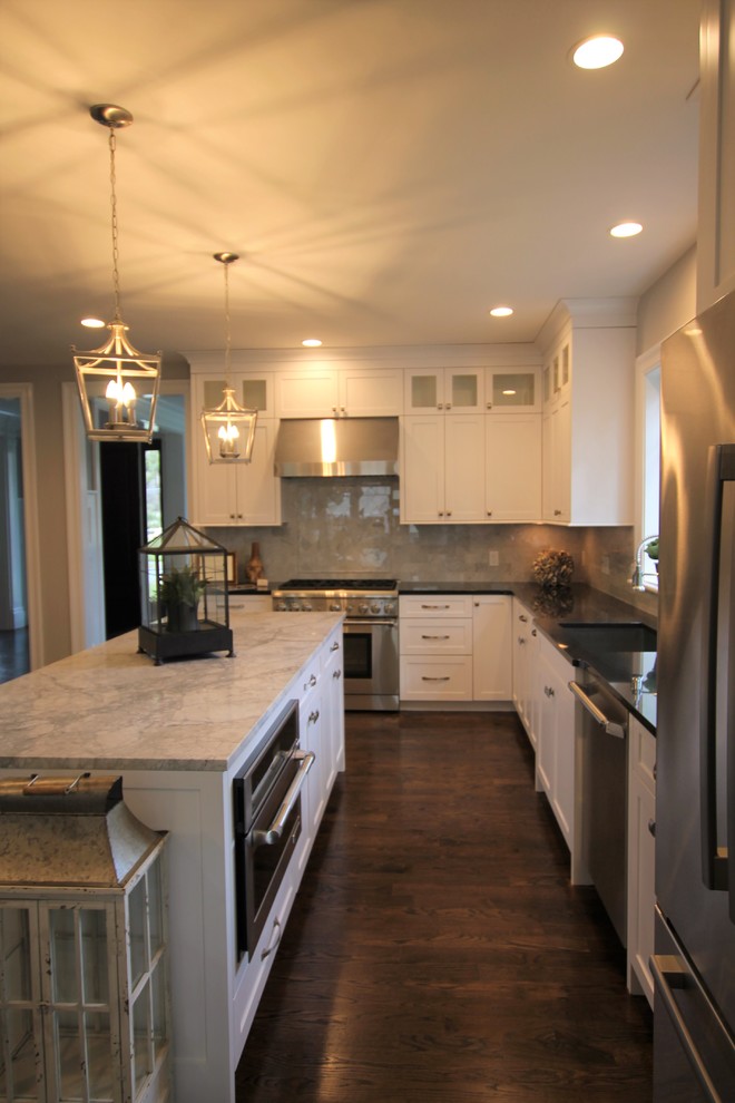 Large transitional l-shaped dark wood floor and brown floor eat-in kitchen photo in Boston with an undermount sink, shaker cabinets, white cabinets, granite countertops, beige backsplash, marble backsplash, stainless steel appliances and an island