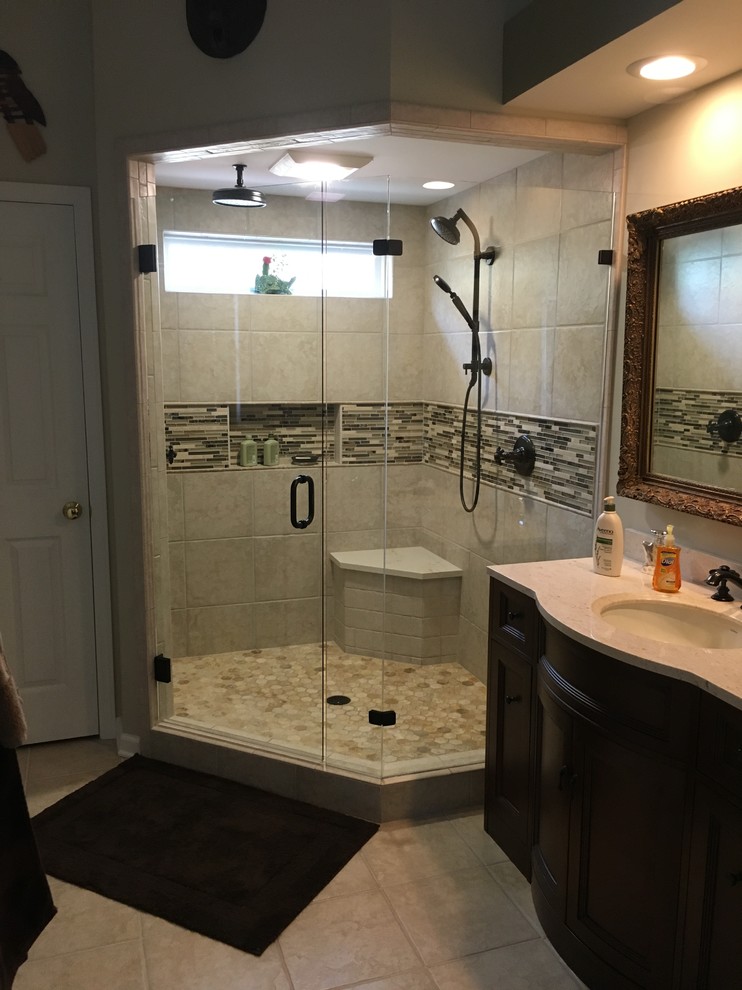 Example of a transitional master porcelain tile porcelain tile corner shower design in Charlotte with furniture-like cabinets, an undermount sink and a hinged shower door