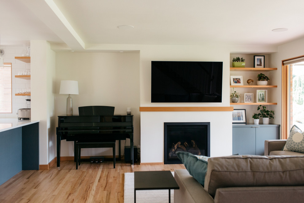 Стильный дизайн: открытая гостиная комната среднего размера в стиле ретро с белыми стенами, светлым паркетным полом, стандартным камином, фасадом камина из штукатурки, телевизором на стене и бежевым полом - последний тренд