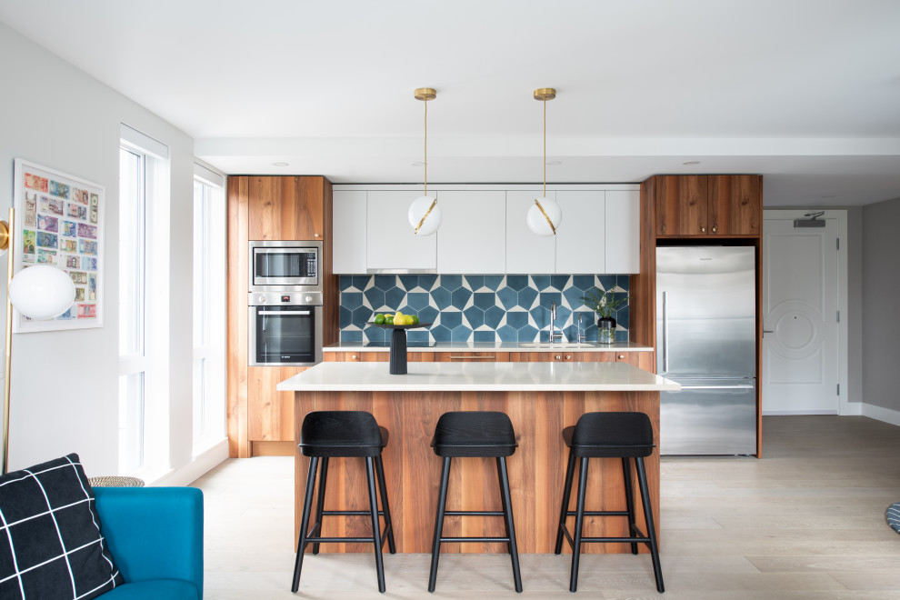 Photo of a mid-sized contemporary galley eat-in kitchen in Vancouver with an undermount sink, flat-panel cabinets, medium wood cabinets, quartzite benchtops, blue splashback, with island, beige benchtop, stainless steel appliances, light hardwood floors and beige floor.