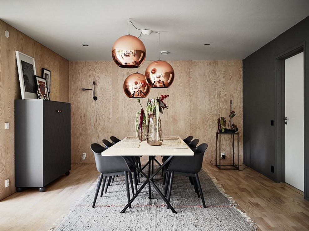 This is an example of a large scandinavian separate dining room in Stockholm with light hardwood floors and black walls.