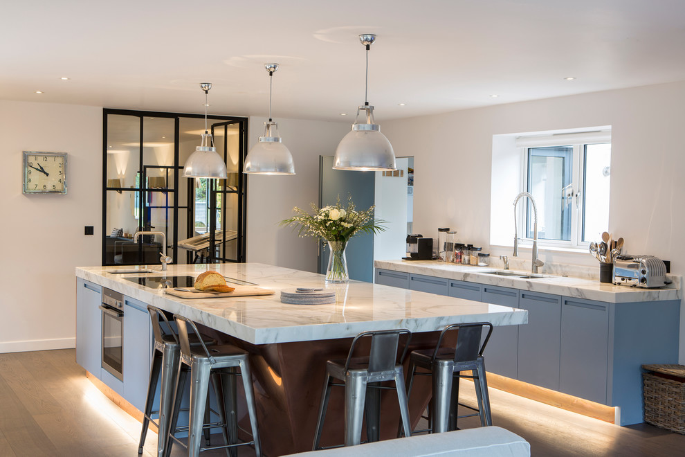 Contemporary kitchen in Sussex with a double-bowl sink, flat-panel cabinets, blue cabinets, light hardwood floors and with island.