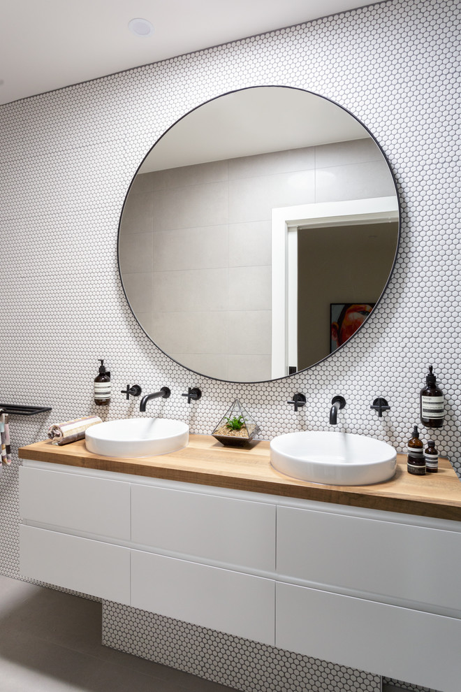 This is an example of a mid-sized contemporary 3/4 bathroom in Melbourne with beaded inset cabinets, white cabinets, an open shower, a wall-mount toilet, pebble tile, a vessel sink and wood benchtops.