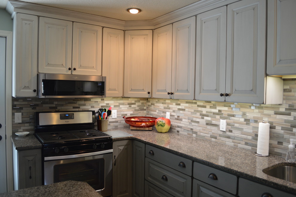 Small transitional l-shaped eat-in kitchen photo with an undermount sink, raised-panel cabinets, white cabinets, quartzite countertops, gray backsplash, porcelain backsplash, stainless steel appliances, an island and gray countertops