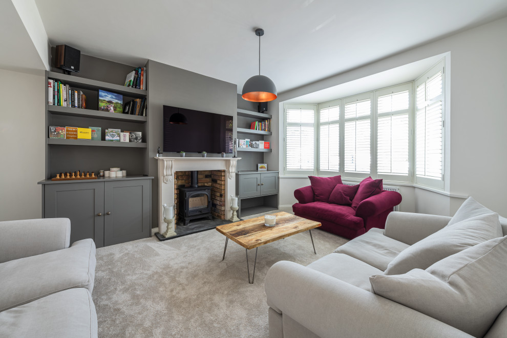 Inspiration for a large modern formal and grey and white enclosed living room in London with a wall mounted tv, grey walls, carpet, a wood burning stove, a brick fireplace surround, grey floors and a chimney breast.