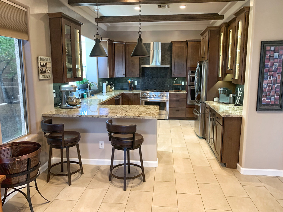 This is an example of a mid-sized contemporary u-shaped open plan kitchen in Phoenix with an undermount sink, shaker cabinets, brown cabinets, granite benchtops, black splashback, mosaic tile splashback, stainless steel appliances, porcelain floors, beige floor, beige benchtop and exposed beam.