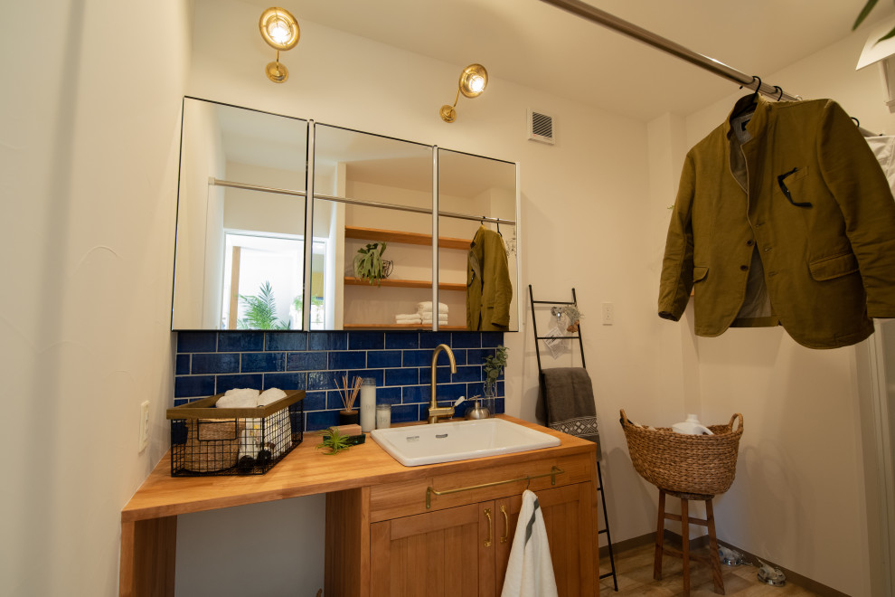 На фото: туалет в стиле рустика с коричневыми фасадами, синей плиткой, керамической плиткой, белыми стенами, светлым паркетным полом, накладной раковиной, столешницей из дерева, коричневым полом и напольной тумбой с