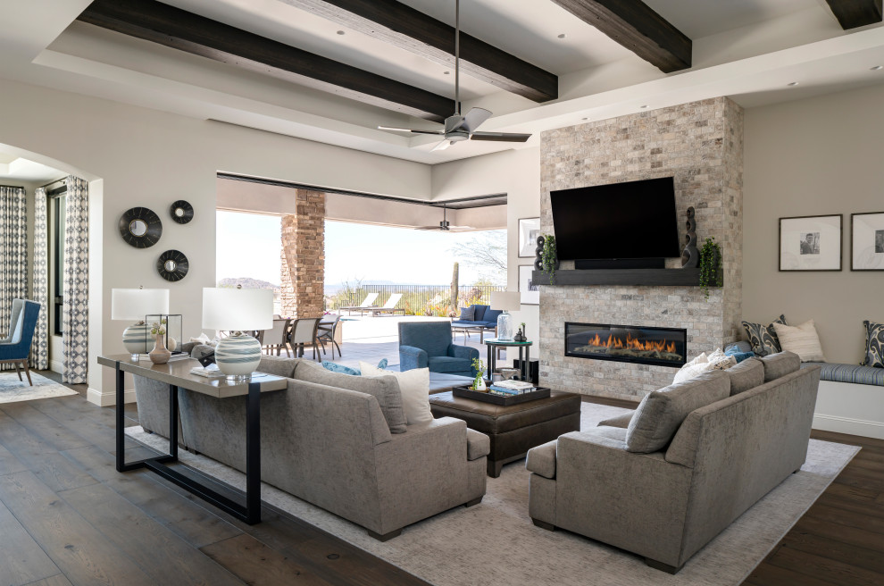 Huge transitional open concept dark wood floor, brown floor and exposed beam living room photo in Phoenix with gray walls, a standard fireplace, a stone fireplace and a wall-mounted tv