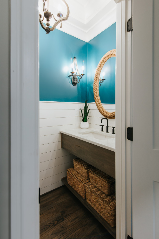Design ideas for a mid-sized beach style powder room in St Louis with medium wood cabinets, a two-piece toilet, blue tile, blue walls, medium hardwood floors, an undermount sink, engineered quartz benchtops, brown floor, white benchtops, a floating vanity and planked wall panelling.