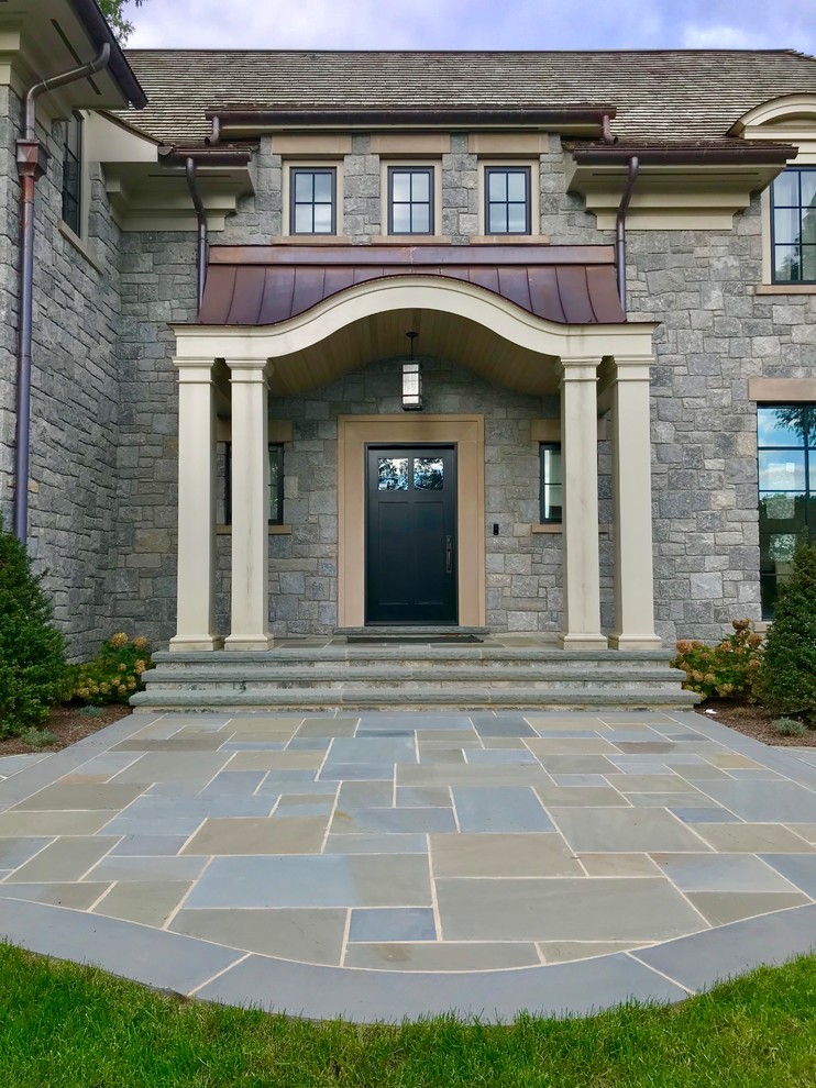 This is an example of an expansive mediterranean front yard garden in New York with natural stone pavers.