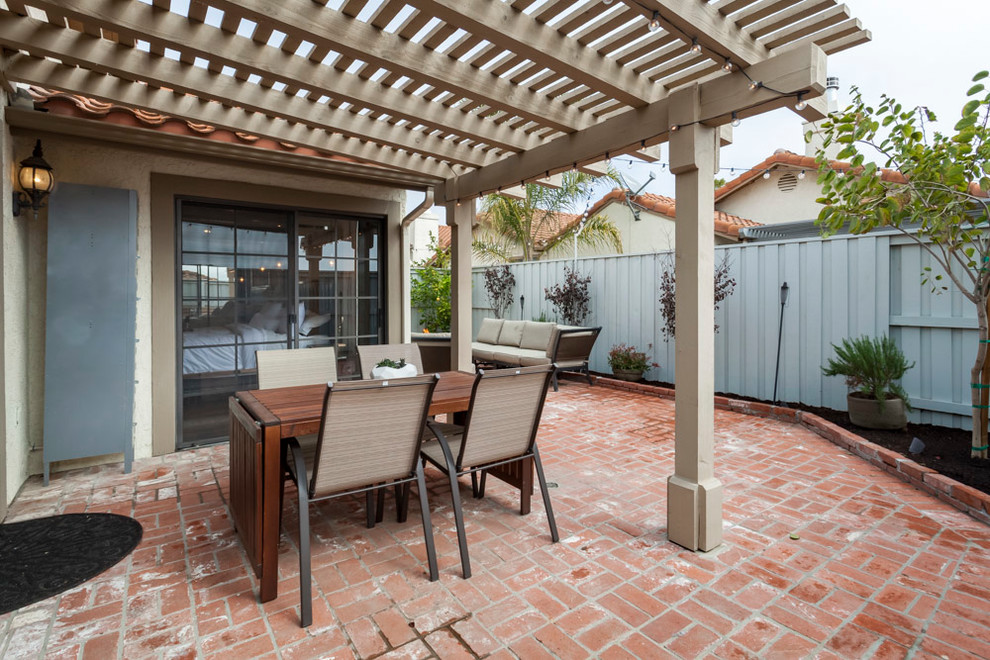 Design ideas for a small transitional courtyard patio in Los Angeles with brick pavers and a pergola.