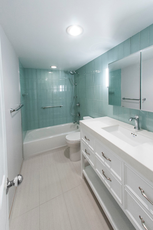 Inspiration for a mid-sized contemporary 3/4 bathroom in DC Metro with furniture-like cabinets, white cabinets, an undermount tub, a shower/bathtub combo, a two-piece toilet, beige tile, glass sheet wall, green walls, an undermount sink, wood benchtops and porcelain floors.