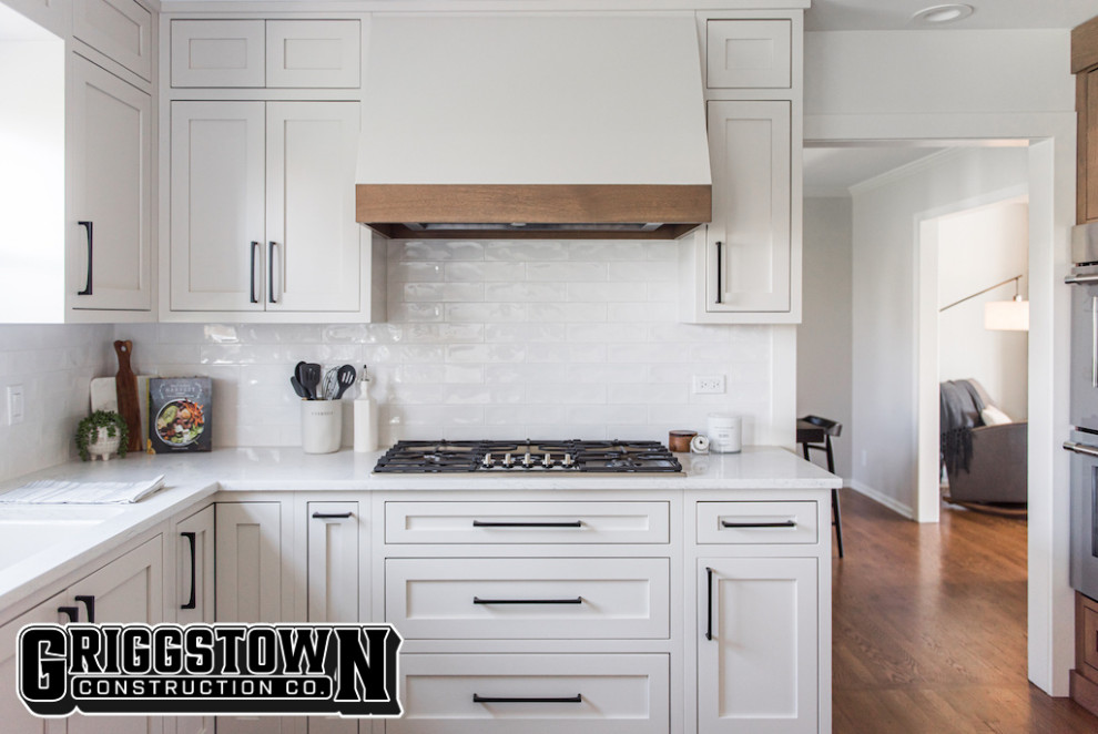 他の地域にある高級な広いモダンスタイルのおしゃれなキッチン (シングルシンク、シェーカースタイル扉のキャビネット、白いキャビネット、珪岩カウンター、白いキッチンパネル、セラミックタイルのキッチンパネル、シルバーの調理設備、無垢フローリング、茶色い床、白いキッチンカウンター) の写真