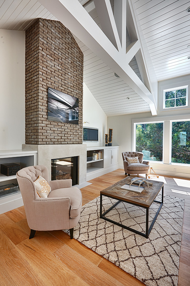 Country living room in San Francisco with white walls, light hardwood floors and a concrete fireplace surround.