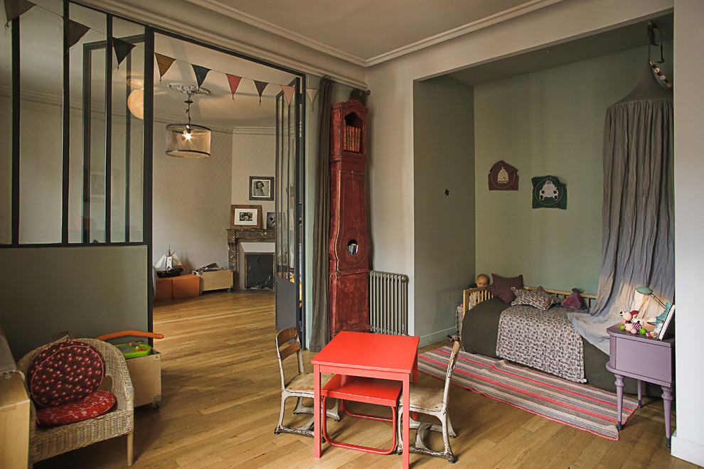 This is an example of a large industrial kids' bedroom for kids 4-10 years old and girls in Paris with green walls and light hardwood floors.