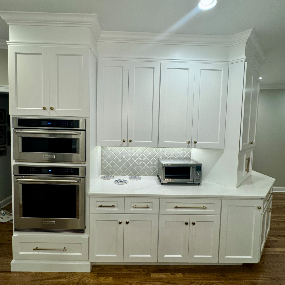 Eat-in kitchen - mid-sized transitional l-shaped medium tone wood floor, brown floor and wallpaper ceiling eat-in kitchen idea in Atlanta with a double-bowl sink, shaker cabinets, white cabinets, granite countertops, gray backsplash, mosaic tile backsplash, stainless steel appliances, an island and white countertops