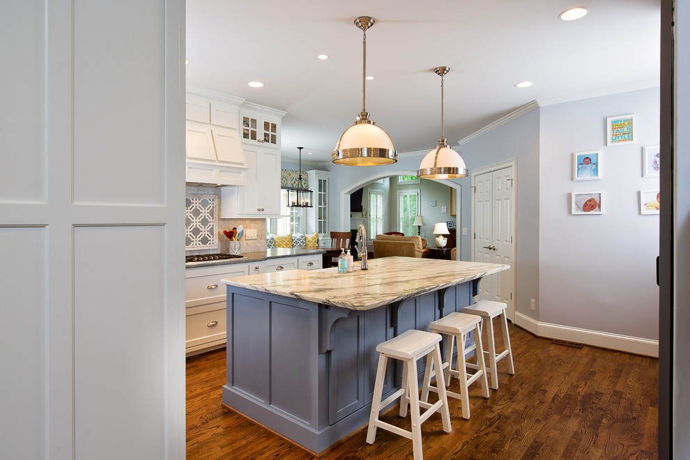 Inspiration for a large transitional l-shaped eat-in kitchen in Atlanta with a farmhouse sink, shaker cabinets, white cabinets, soapstone benchtops, white splashback, stone tile splashback, stainless steel appliances, medium hardwood floors and with island.