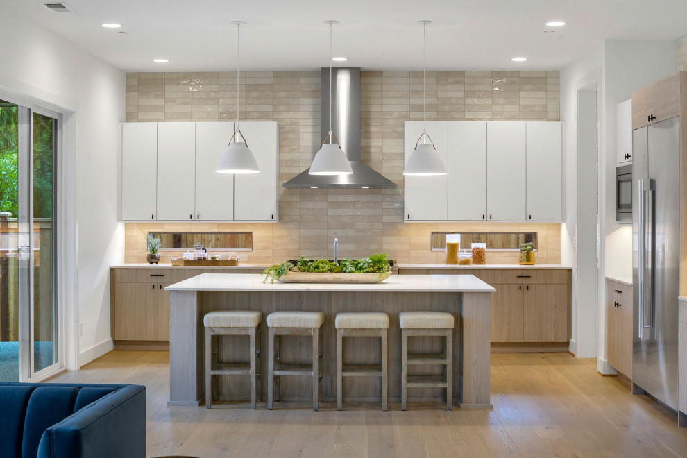 Photo of a large contemporary l-shaped kitchen pantry in Seattle with a drop-in sink, flat-panel cabinets, white cabinets, quartz benchtops, cement tile splashback, stainless steel appliances, light hardwood floors, with island, brown floor and white benchtop.