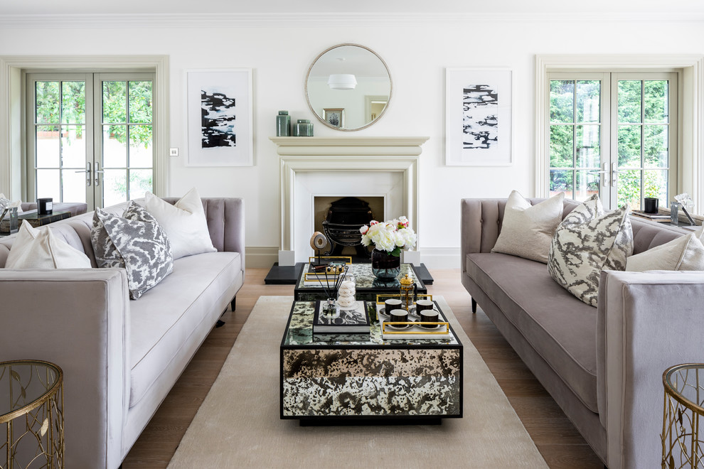 Photo of a transitional open concept living room in London with white walls, light hardwood floors, a standard fireplace, a stone fireplace surround, no tv and beige floor.