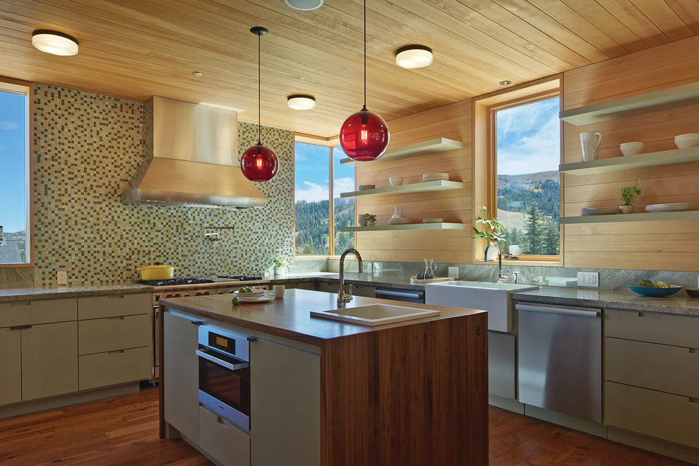 Mid-sized contemporary l-shaped kitchen in San Francisco with medium hardwood floors, with island, a farmhouse sink, flat-panel cabinets, green cabinets, mosaic tile splashback and stainless steel appliances.
