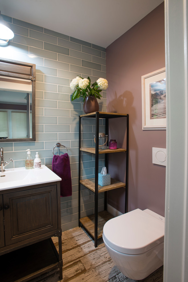 Small contemporary 3/4 bathroom in New York with raised-panel cabinets, dark wood cabinets, a wall-mount toilet, blue tile, ceramic tile, purple walls, ceramic floors and an undermount sink.