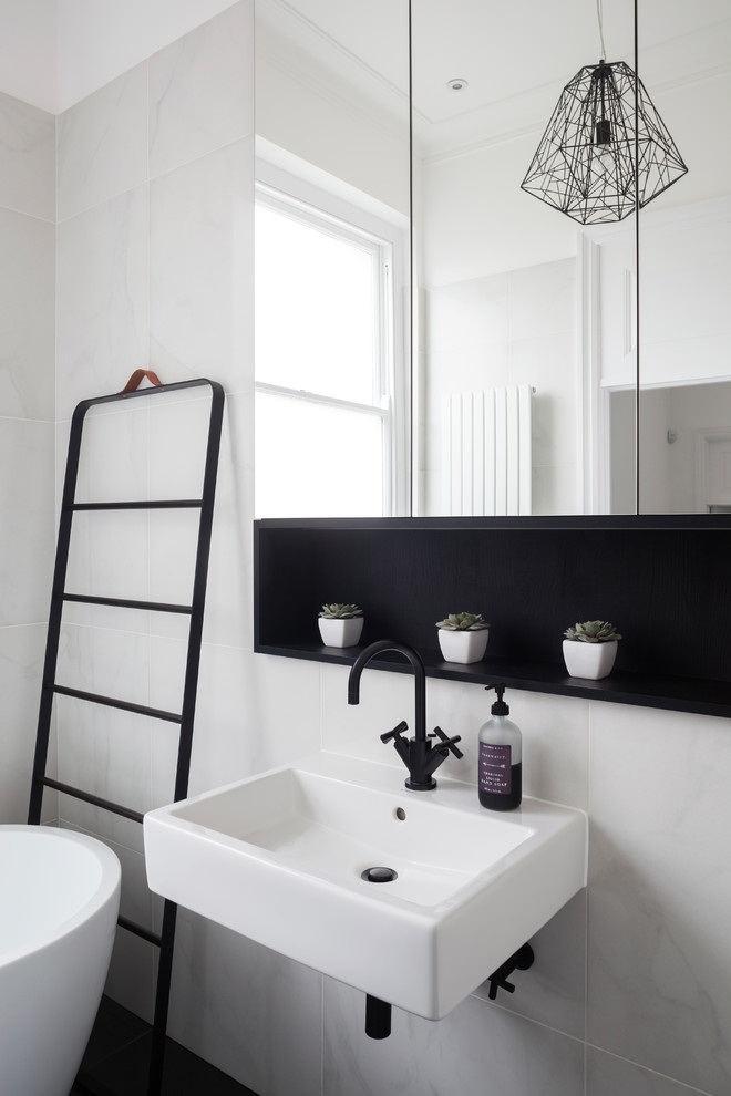 Photo of a medium sized contemporary bathroom in London with a freestanding bath, marble tiles, grey walls and a wall-mounted sink.