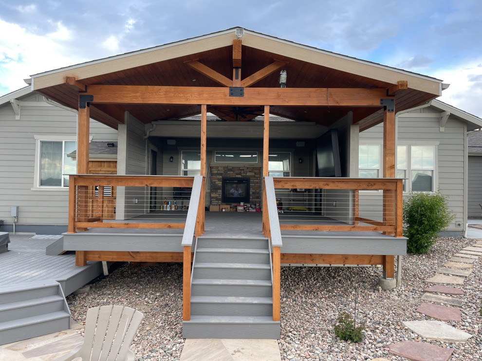 Mid-sized arts and crafts backyard and ground level deck in Denver with a roof extension and cable railing.