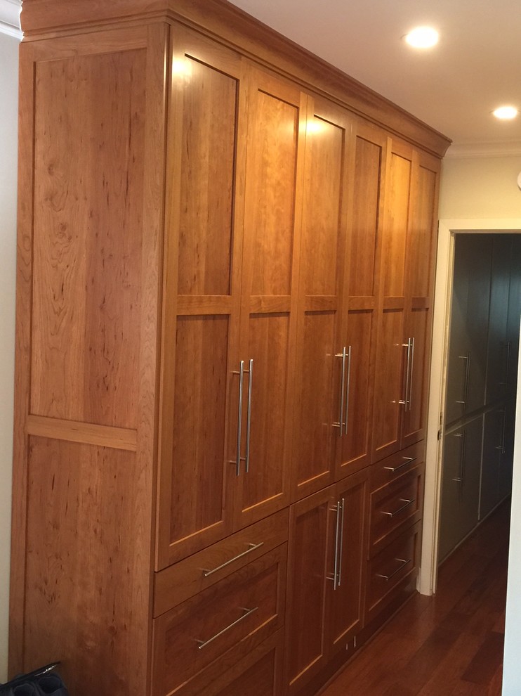 Photo of a small contemporary men's built-in wardrobe in Los Angeles with shaker cabinets, medium wood cabinets and light hardwood floors.