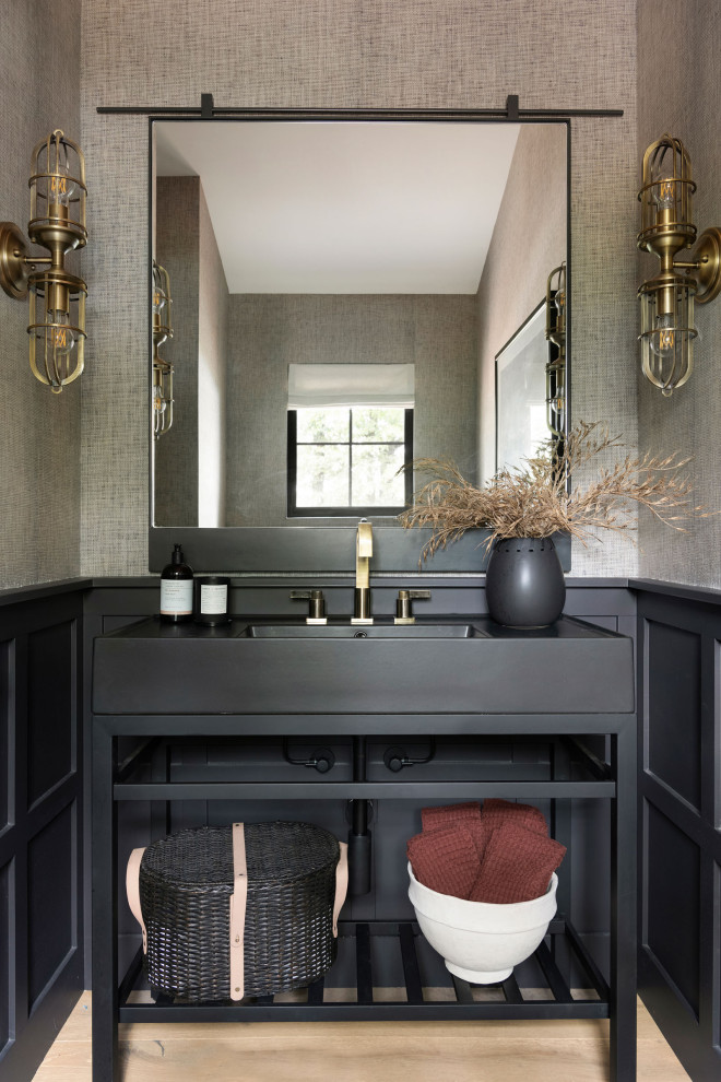 This is an example of a beach style powder room in Minneapolis with open cabinets, black cabinets, brown walls, an integrated sink, beige floor, black benchtops, a freestanding vanity and wallpaper.