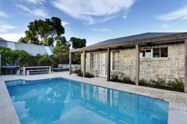 This is an example of a mid-sized beach style backyard rectangular aboveground pool in Melbourne with a pool house and tile.