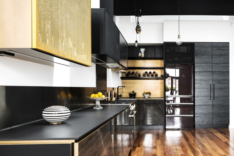 Inspiration for a mid-sized industrial l-shaped open plan kitchen in Melbourne with an undermount sink, black cabinets, quartz benchtops, metallic splashback, metal splashback, black appliances, medium hardwood floors, brown floor, black benchtop and vaulted.