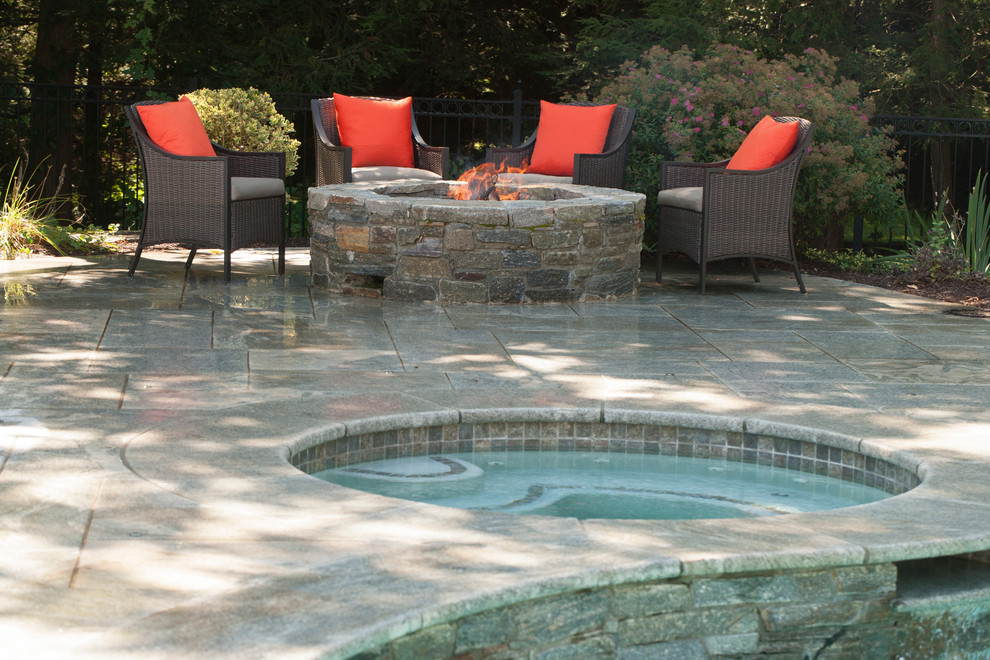 This is an example of a mid-sized country backyard patio in New York with a fire feature, natural stone pavers and no cover.