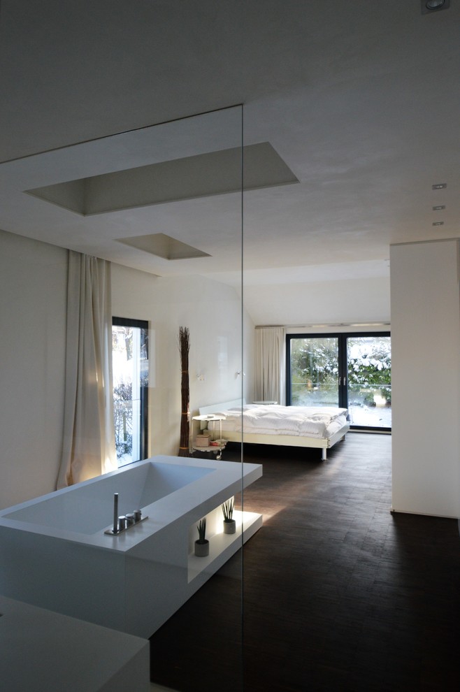 Photo of a large contemporary loft-style bedroom in Stuttgart with white walls, no fireplace and brown floor.