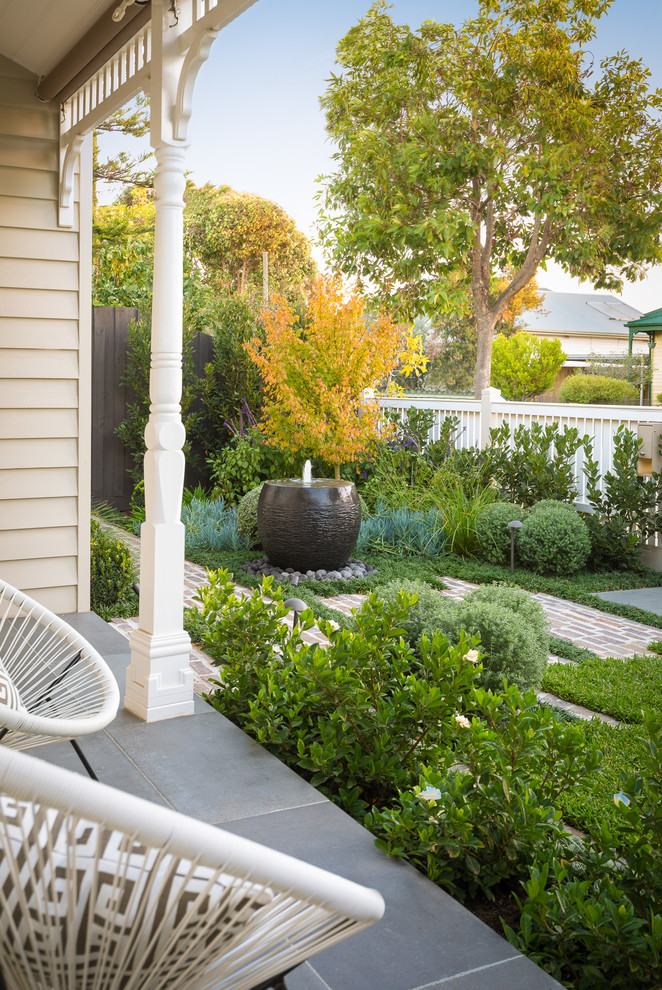 This is an example of a small country front yard garden in Melbourne with a water feature and natural stone pavers.