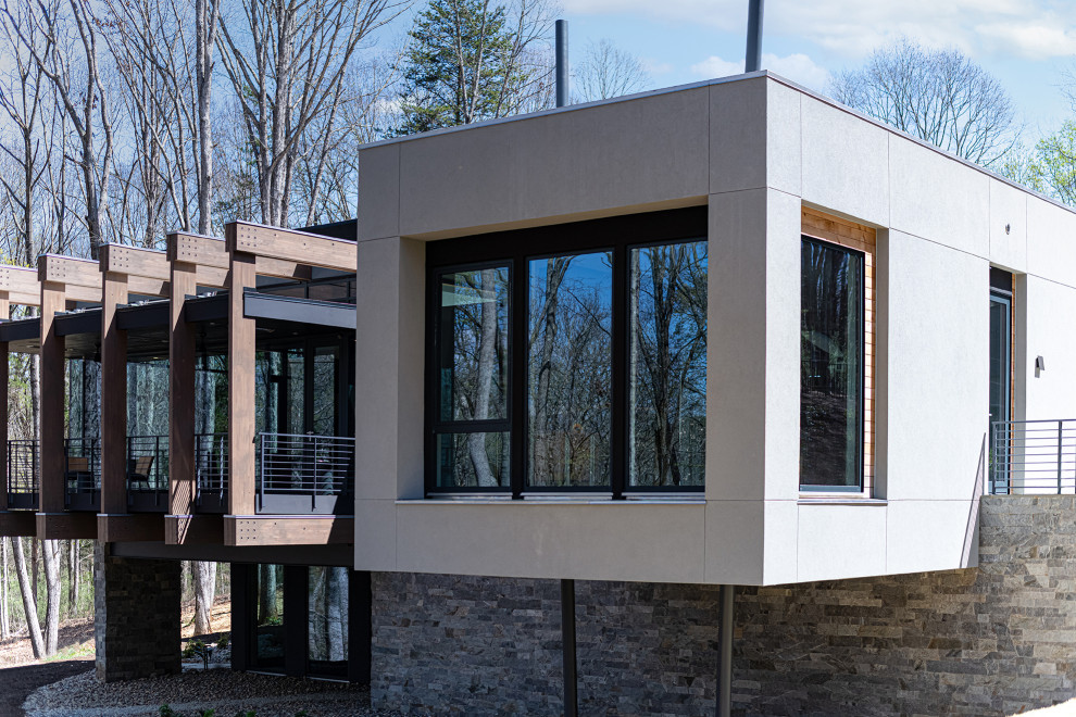 Inspiration för stora moderna grå hus, med två våningar, stuckatur, platt tak och tak i mixade material