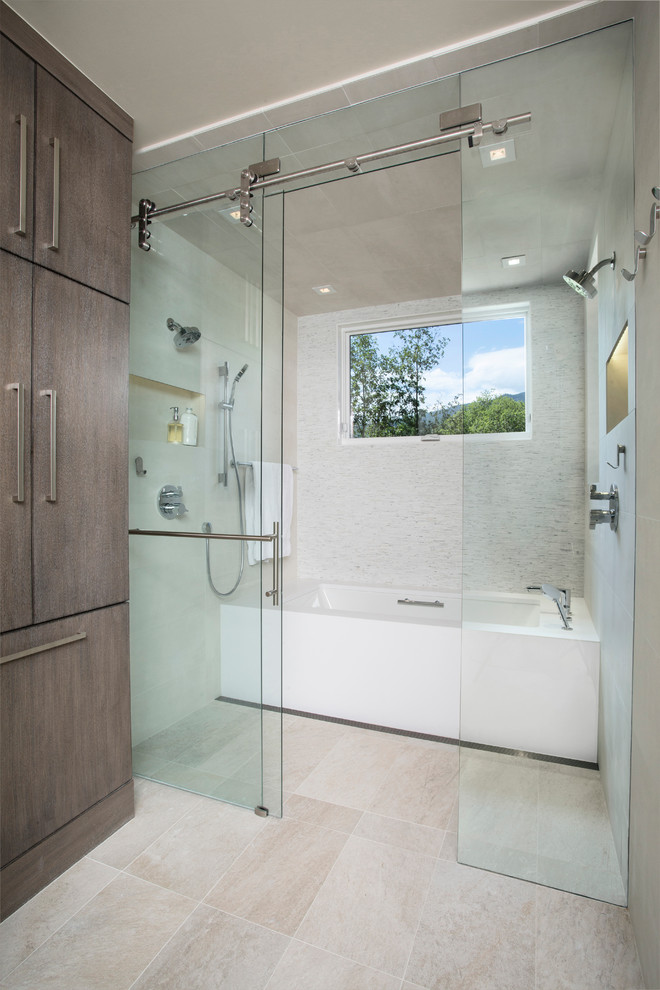 This is an example of a large contemporary master bathroom in Denver with flat-panel cabinets, a curbless shower, an integrated sink, medium wood cabinets, a two-piece toilet, white tile, matchstick tile, white walls, an alcove tub, limestone floors, beige floor and a sliding shower screen.