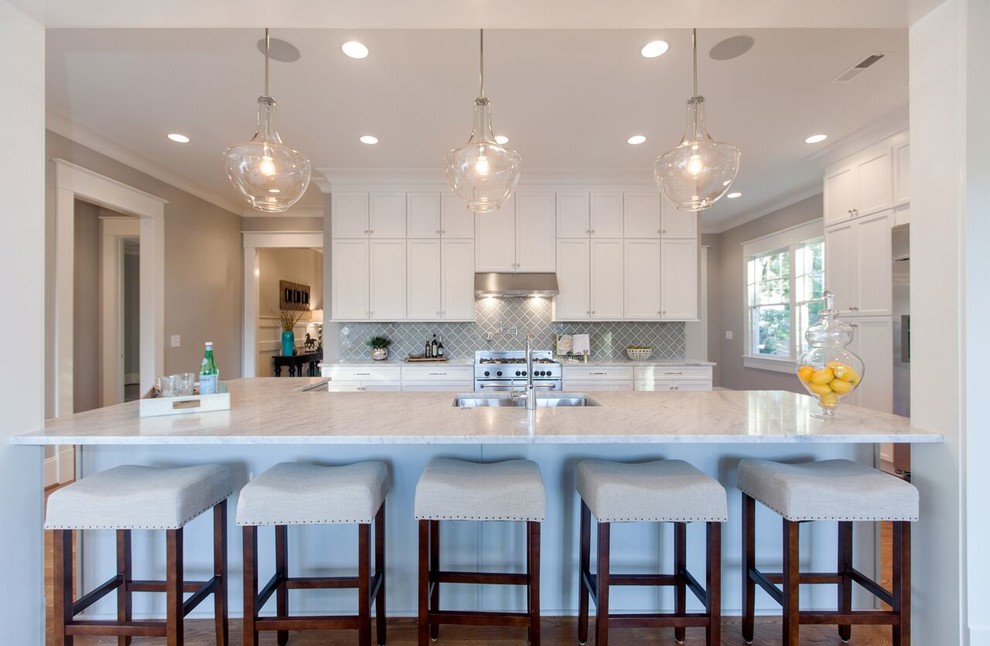 Mid-sized transitional single-wall medium tone wood floor open concept kitchen photo in Raleigh with a single-bowl sink, shaker cabinets, white cabinets, marble countertops, gray backsplash, stainless steel appliances and an island