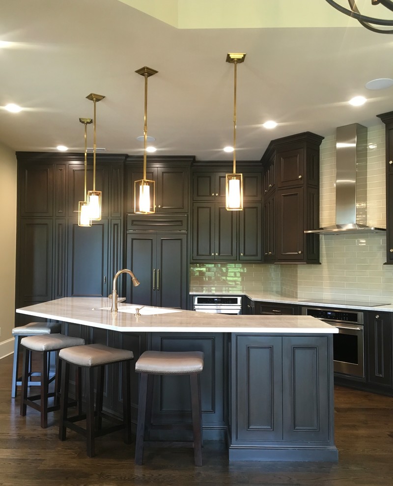 Inspiration for a large transitional l-shaped eat-in kitchen with a drop-in sink, raised-panel cabinets, dark wood cabinets, quartzite benchtops, beige splashback, ceramic splashback, stainless steel appliances, dark hardwood floors, with island, brown floor and beige benchtop.