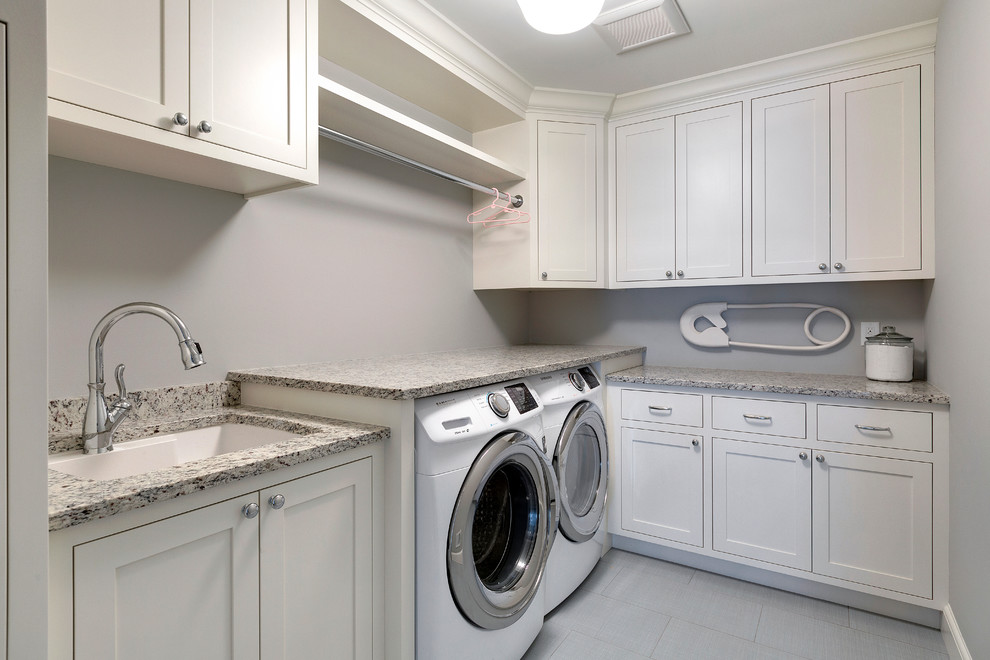 Mid-sized transitional l-shaped dedicated laundry room in Minneapolis with an undermount sink, recessed-panel cabinets, white cabinets, granite benchtops, grey walls, ceramic floors and a side-by-side washer and dryer.