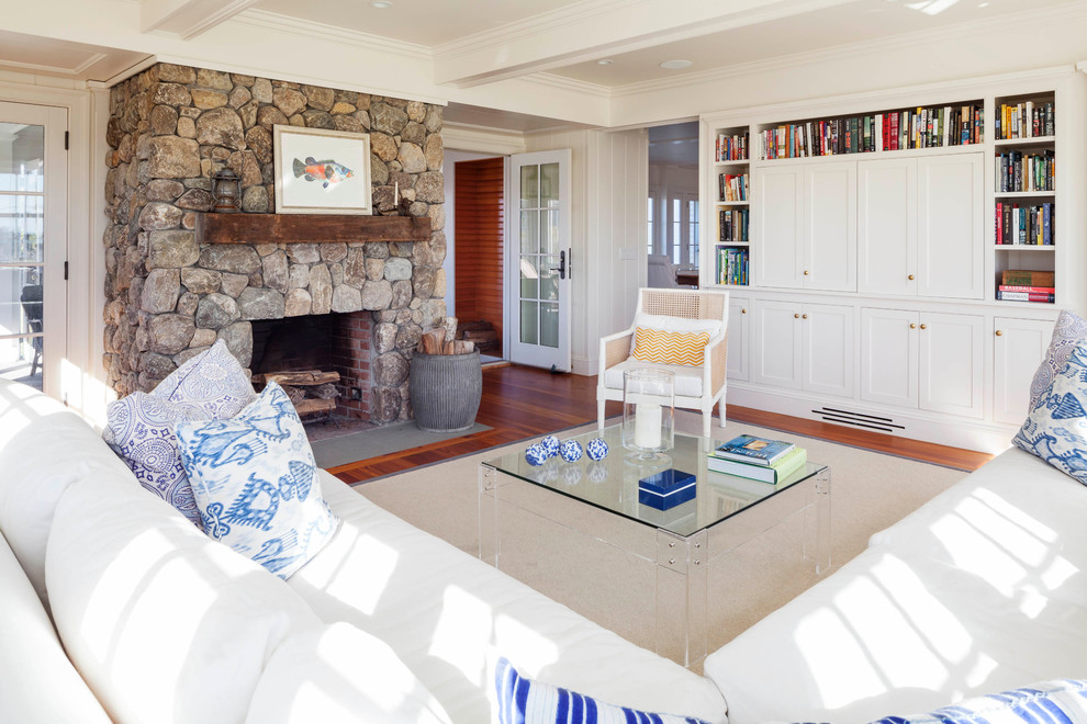 Photo of a large beach style enclosed family room in Providence with a library, white walls, medium hardwood floors, a standard fireplace and a stone fireplace surround.