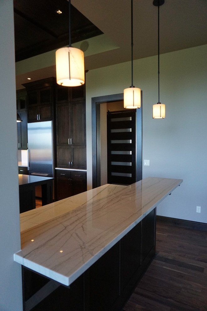 Example of a large trendy u-shaped light wood floor home design design with a single-bowl sink, shaker cabinets, dark wood cabinets, quartz countertops, white backsplash, ceramic backsplash, stainless steel appliances and an island